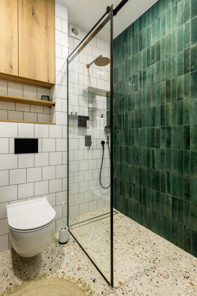 A white, beige, and green bathroom featuring a curbless shower and linear drain.