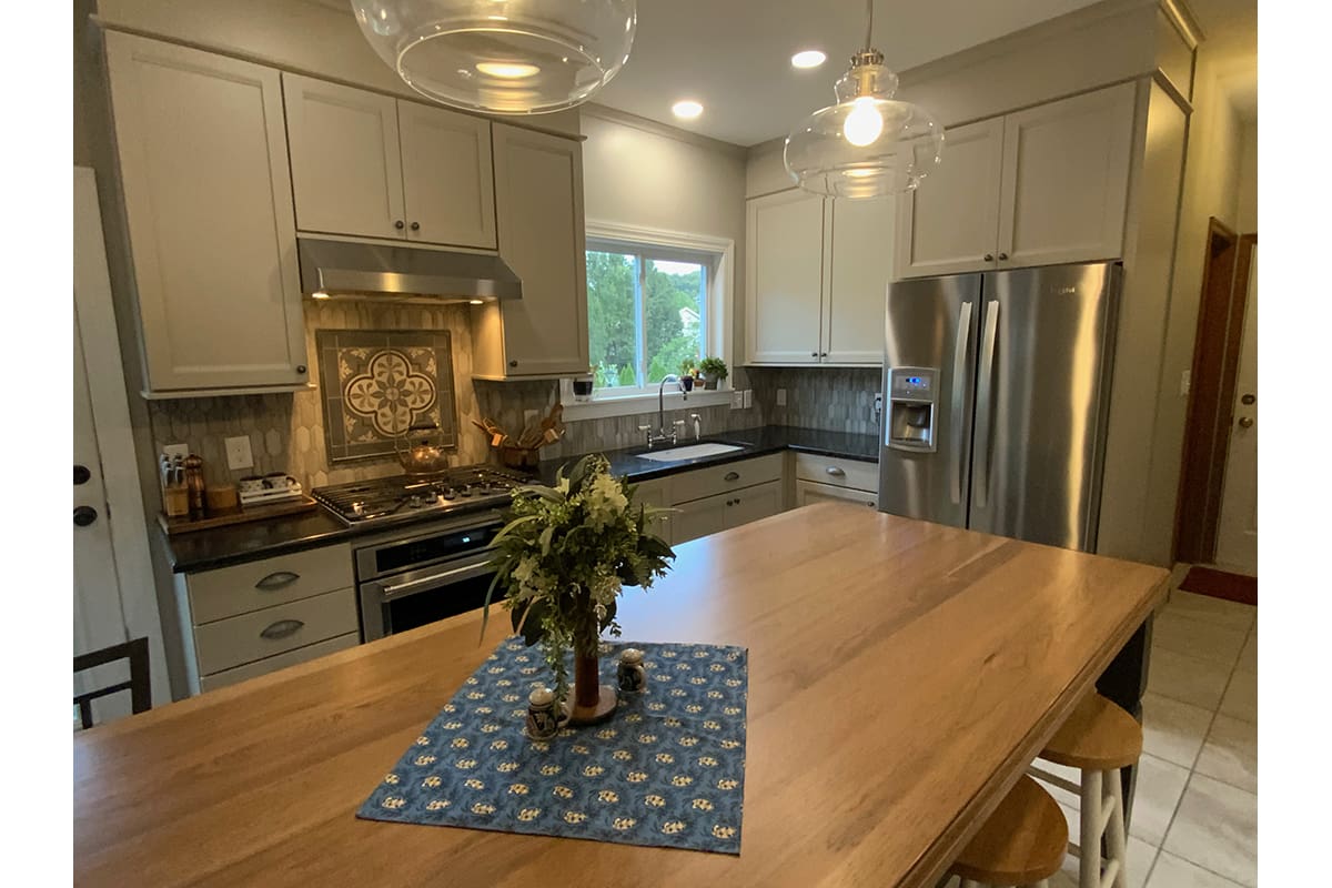 Custom cabinetry in a designer kitchen, featuring stainless steel appliances and a reclaimed wood countertop.