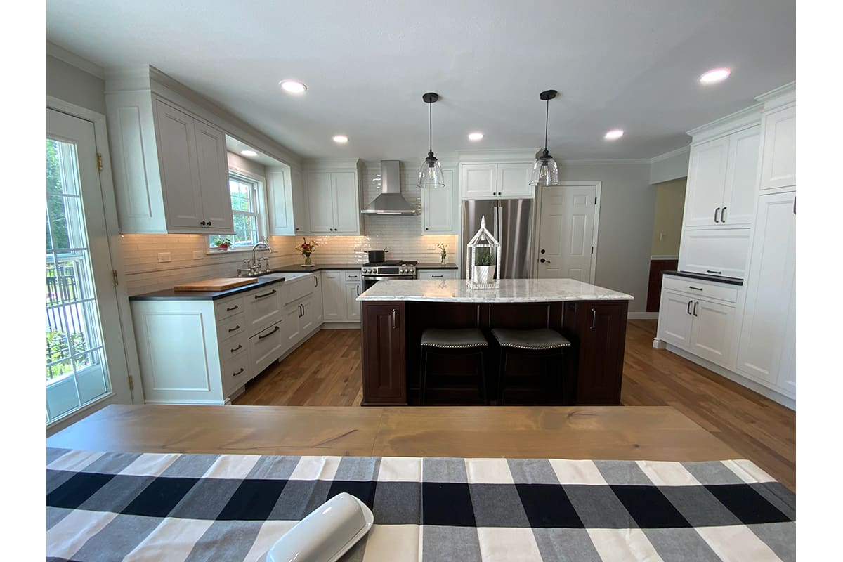 A transitional kitchen remodel with a dark island and light perimeter cabinetry.